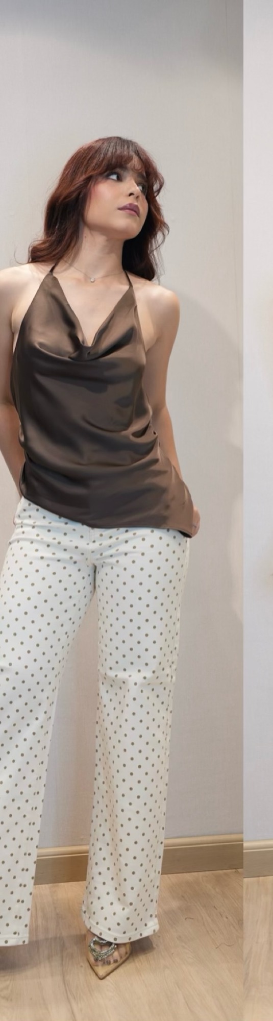 Mujer con top de seda marrón y pantalón blanco de lunares