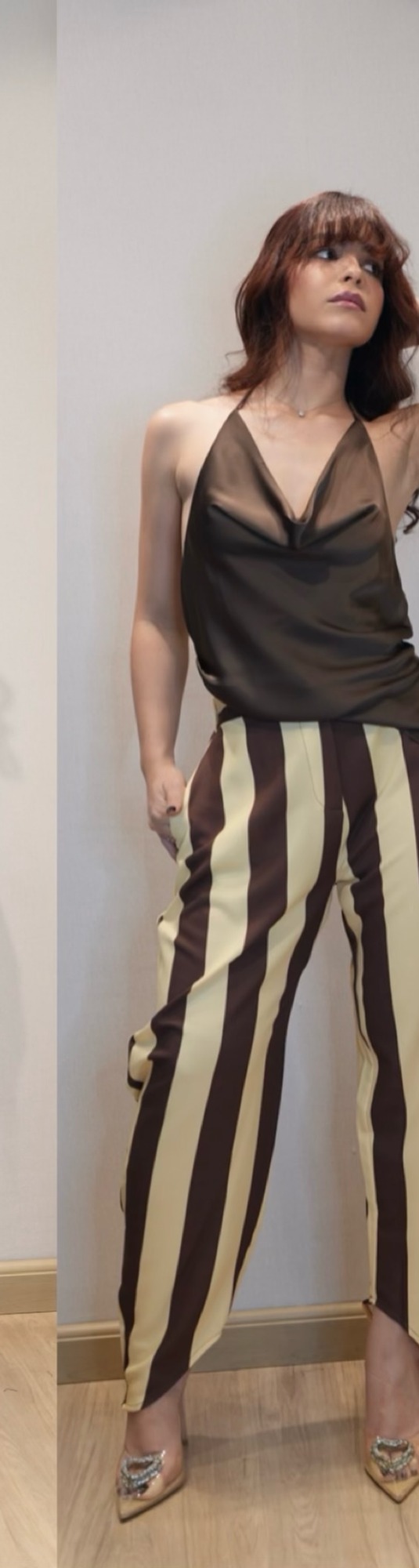 Mujer con top de seda marrón y pantalón de rayas anchas